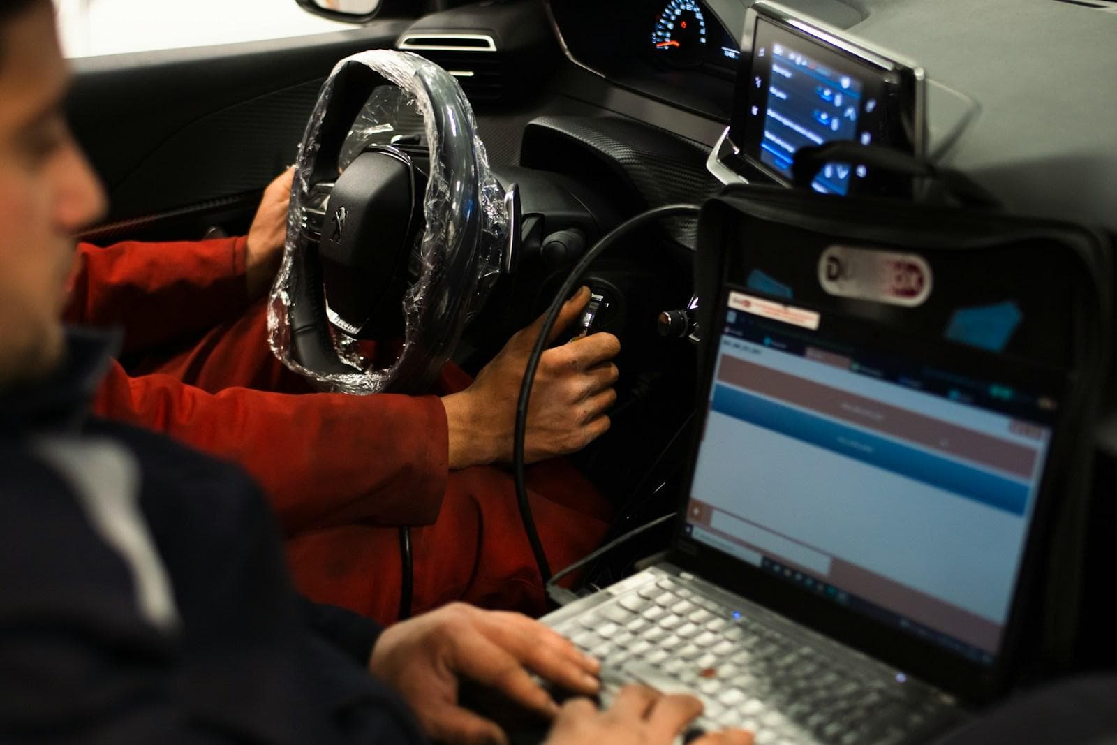 Technician running a diagnostic scan on a laptop connected to a car