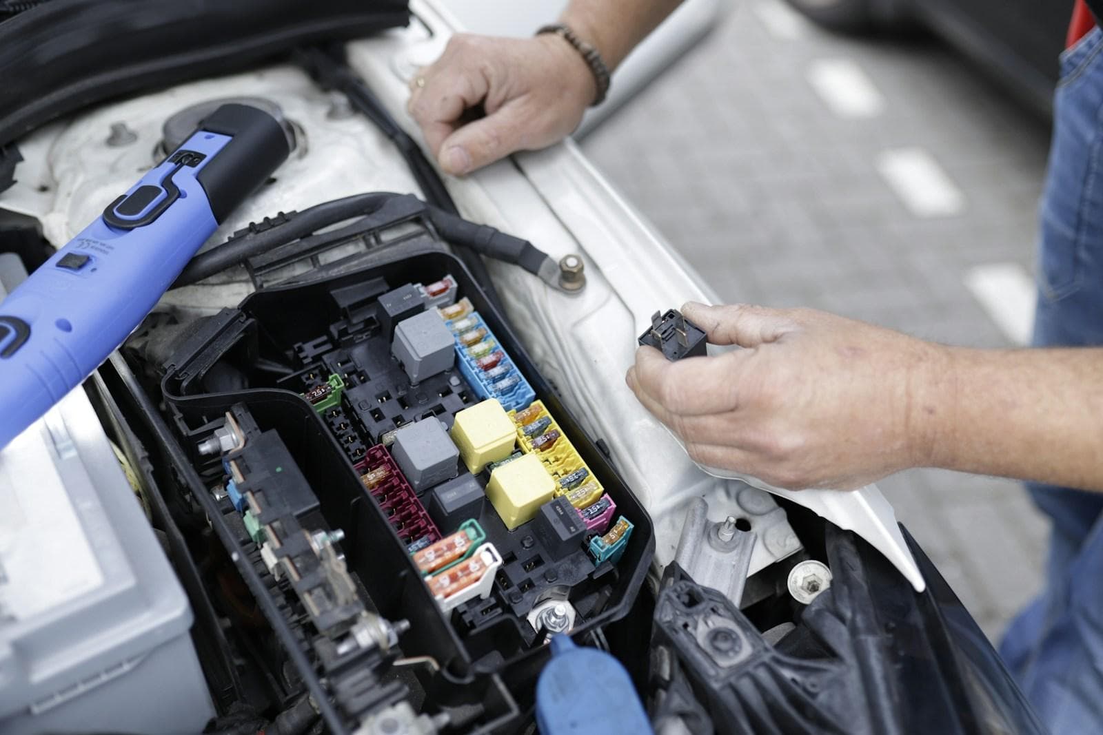 Technician testing a vehicle fuse box and wiring