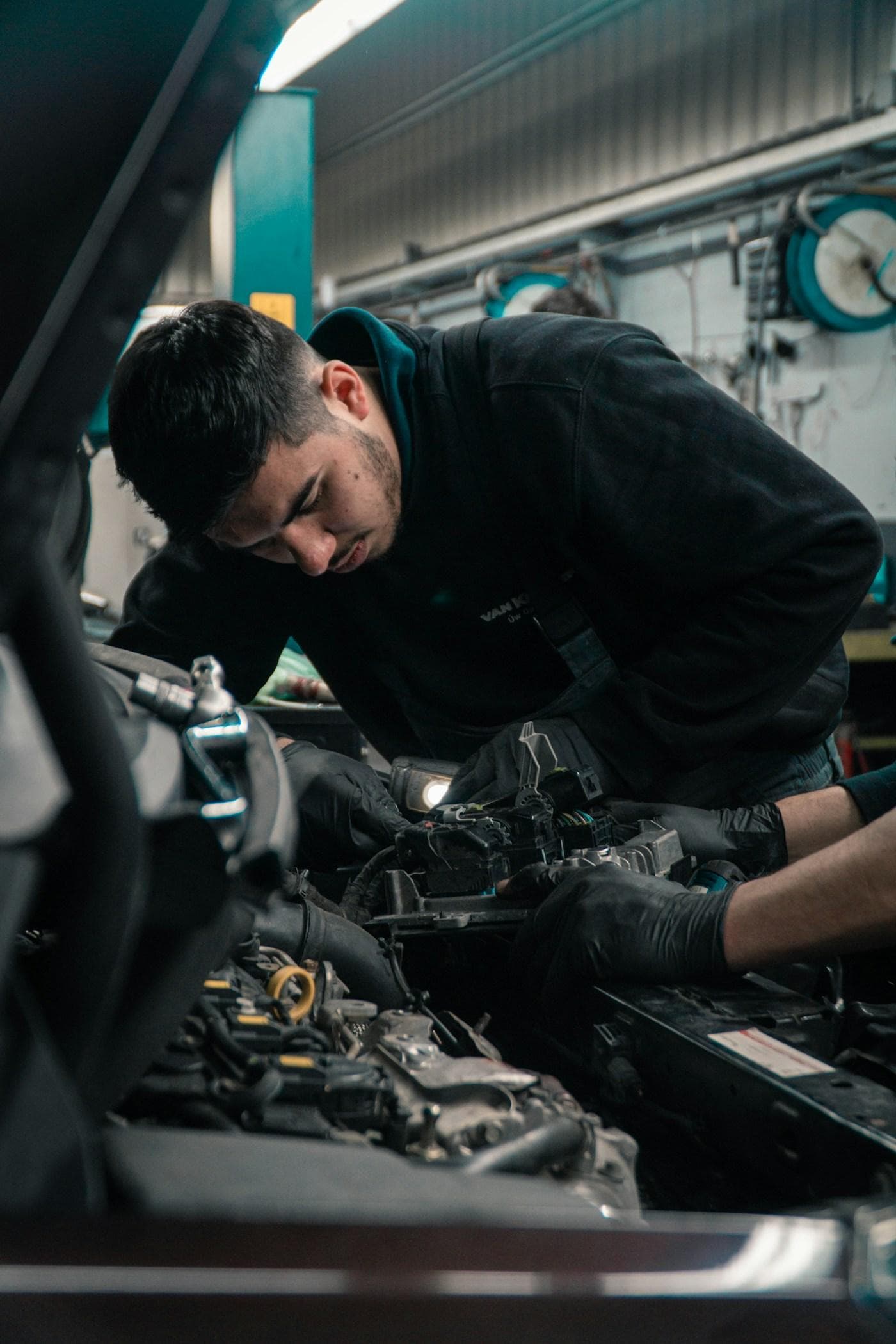 Mechanic working in an engine bay with gloved hands
