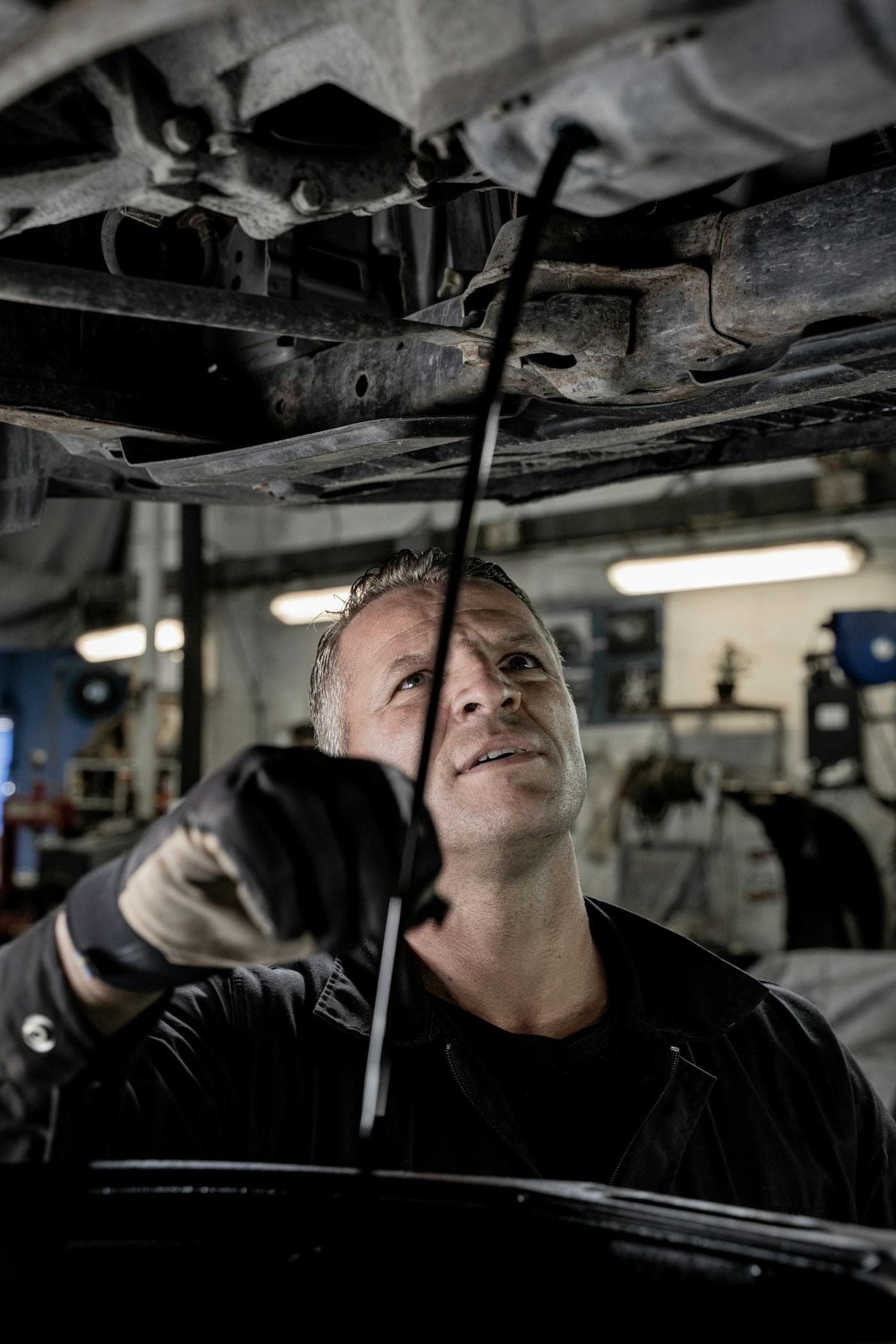 Mechanic checking under a car raised on a hoist