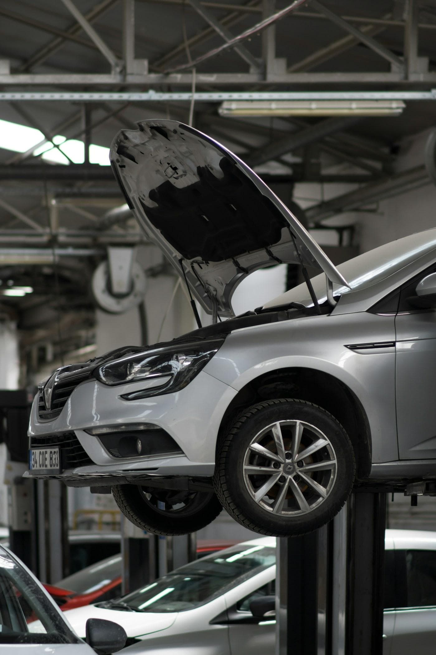 Car on a hoist in a workshop bay with the bonnet open