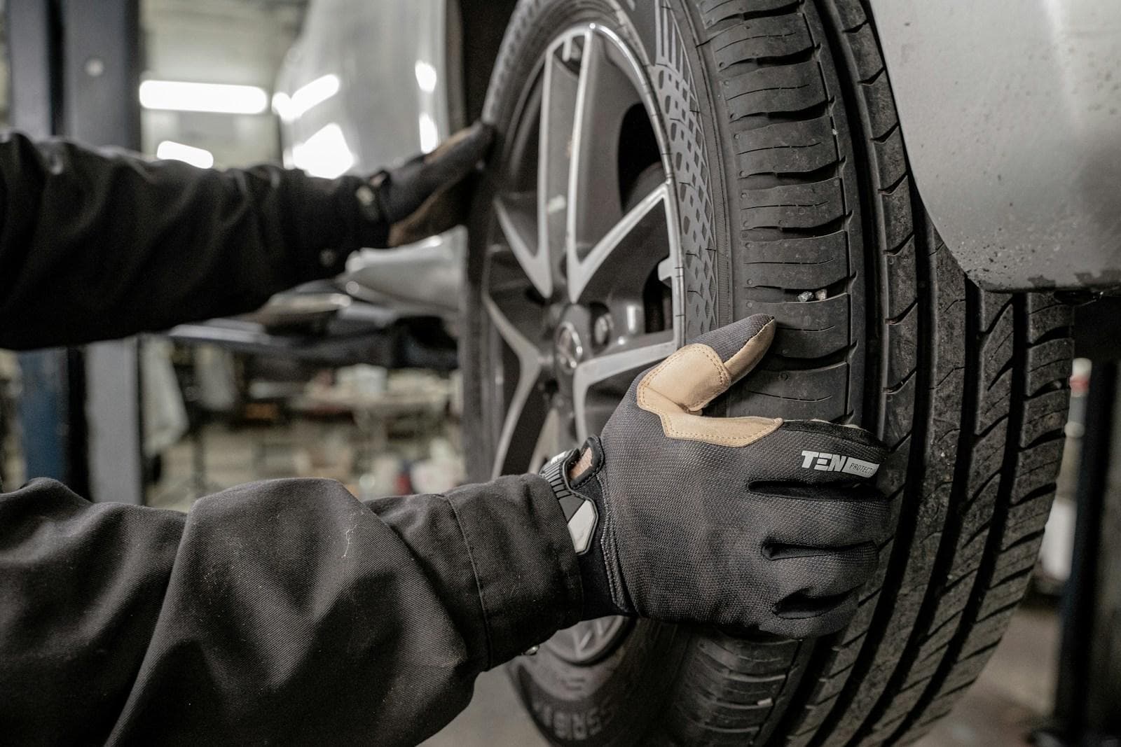 Gloved hands fitting a wheel and tyre to a car